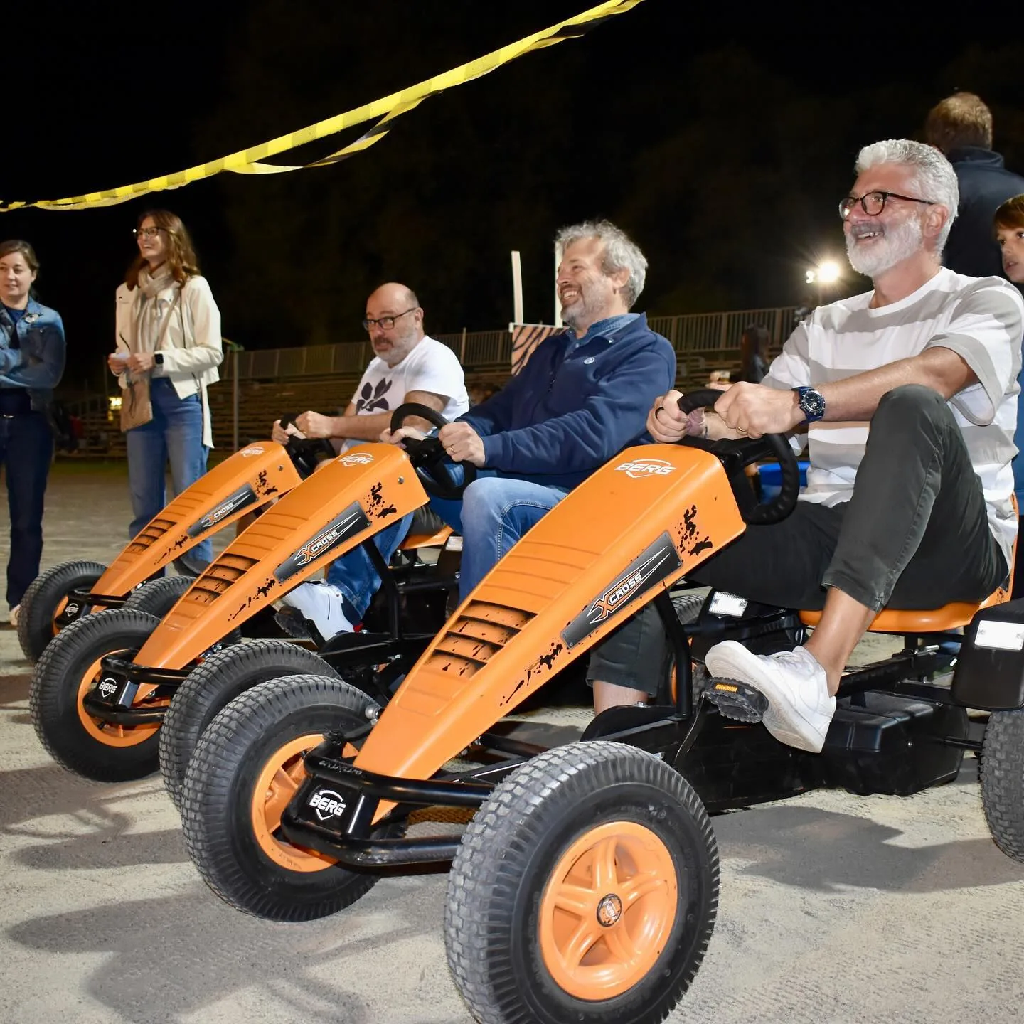 Adulti in fila sui go-kart a pedali